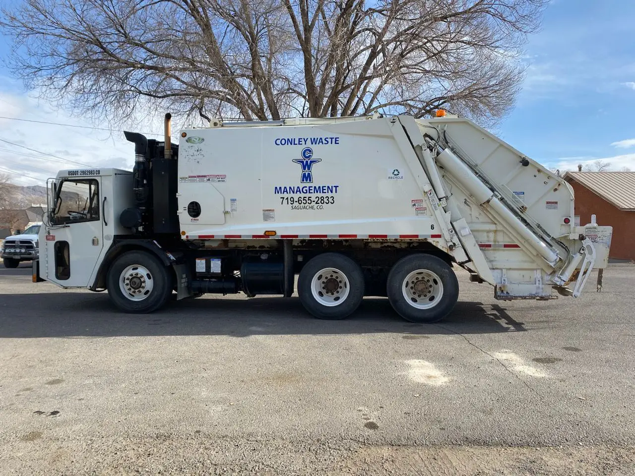 A garbage truck parked in the middle of a parking lot.