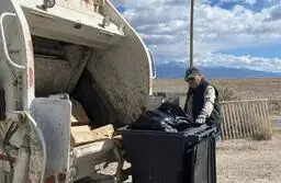 A man standing next to a garbage truck.